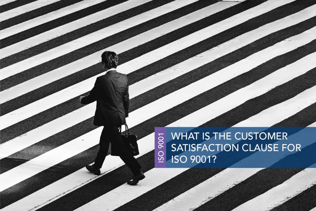 Black and white image of a Person in a black suit tuned away from the camera and walking across a black and white striped road