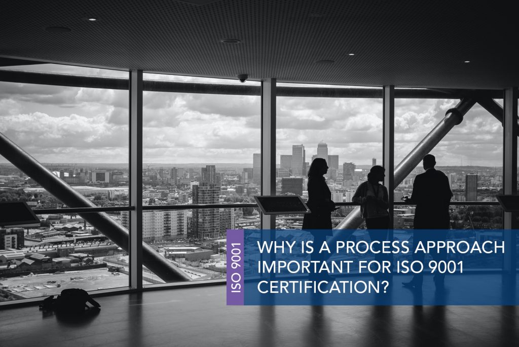 Black and white image of an empty room with large windows overlooking the city with many buildings