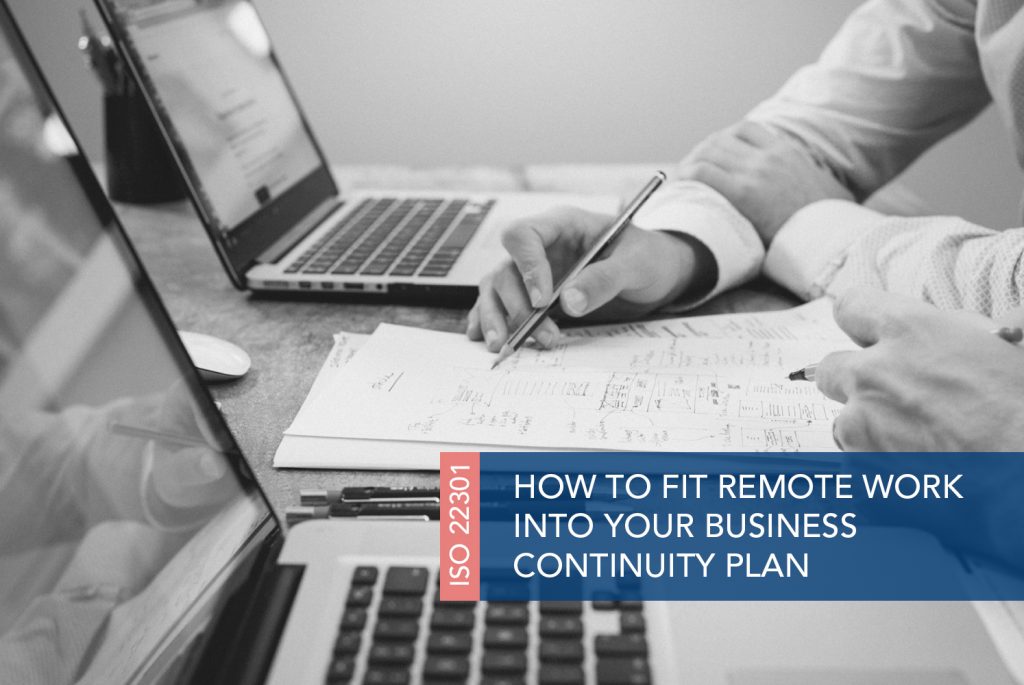 Black and white image of a person at a table with a pen and computer. They are looking at a written on piece of paper