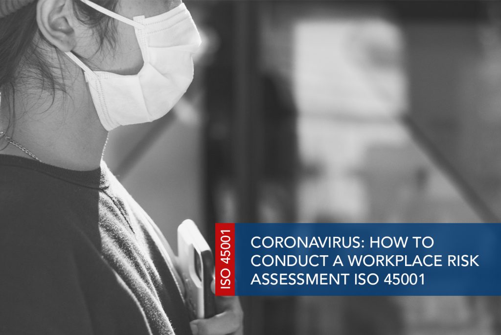 Black and white image of a side-on view of a person wearing a mask and holding a phone to their body